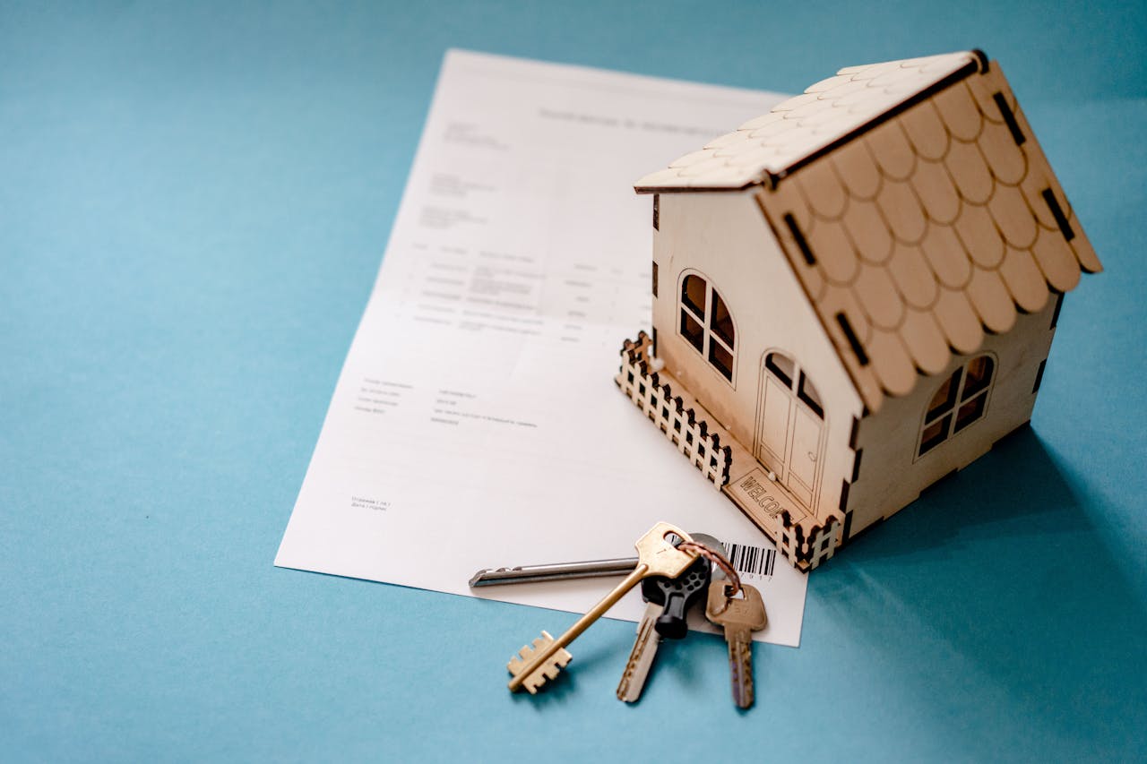gallery-3 Miniature wooden house with keys and contract symbolizing real estate transactions.