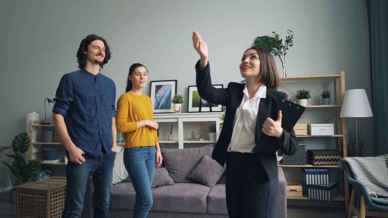 services-01 Real estate agent presenting a modern apartment to potential buyers in a stylish living room.