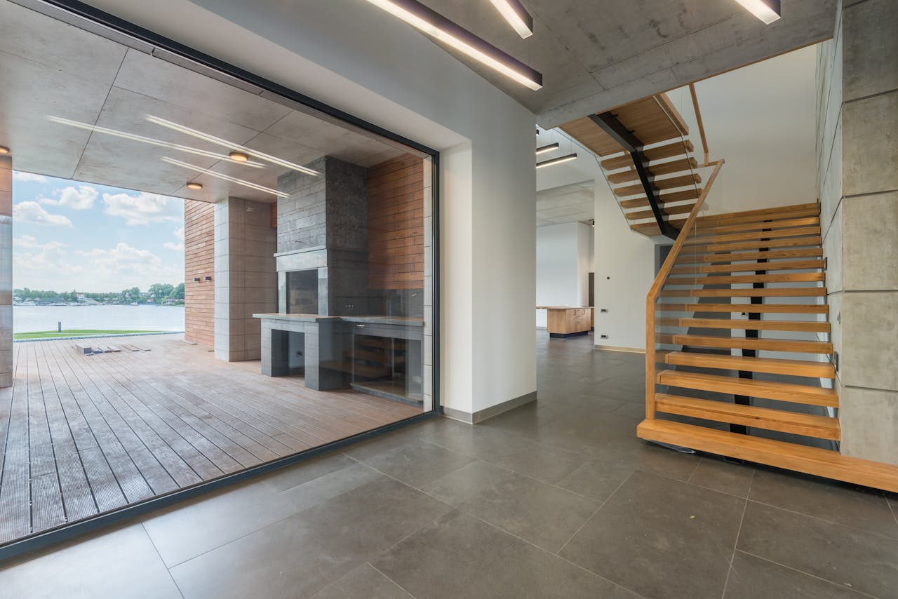 services-03 Spacious interior with wooden staircase and exit to terrace in loft apartment on daytime
