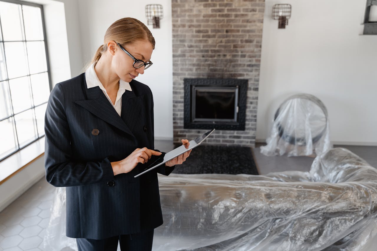 gallery-4 A real estate agent in a suit uses a digital tablet to review documents in a modern living room.