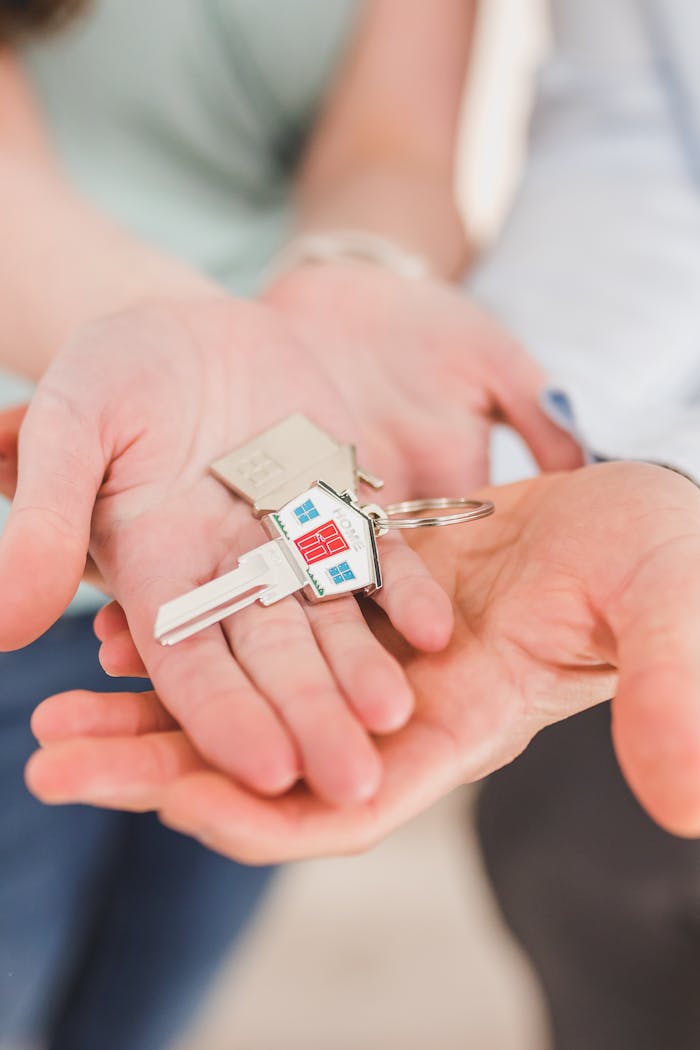contact-img Close-up of hands holding a key with a house-shaped keychain, symbolizing new beginnings.