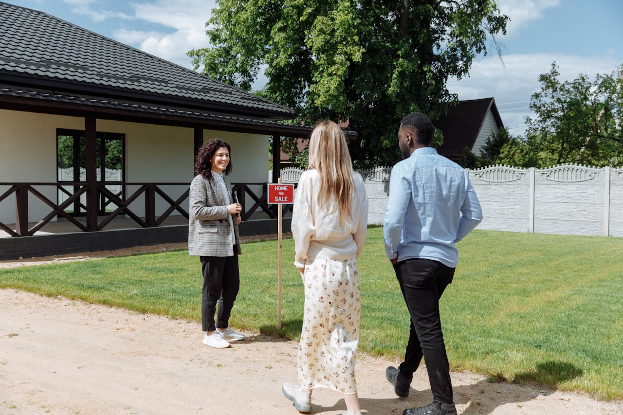 services-02 A diverse group viewing a house for sale with a real estate agent outdoors.